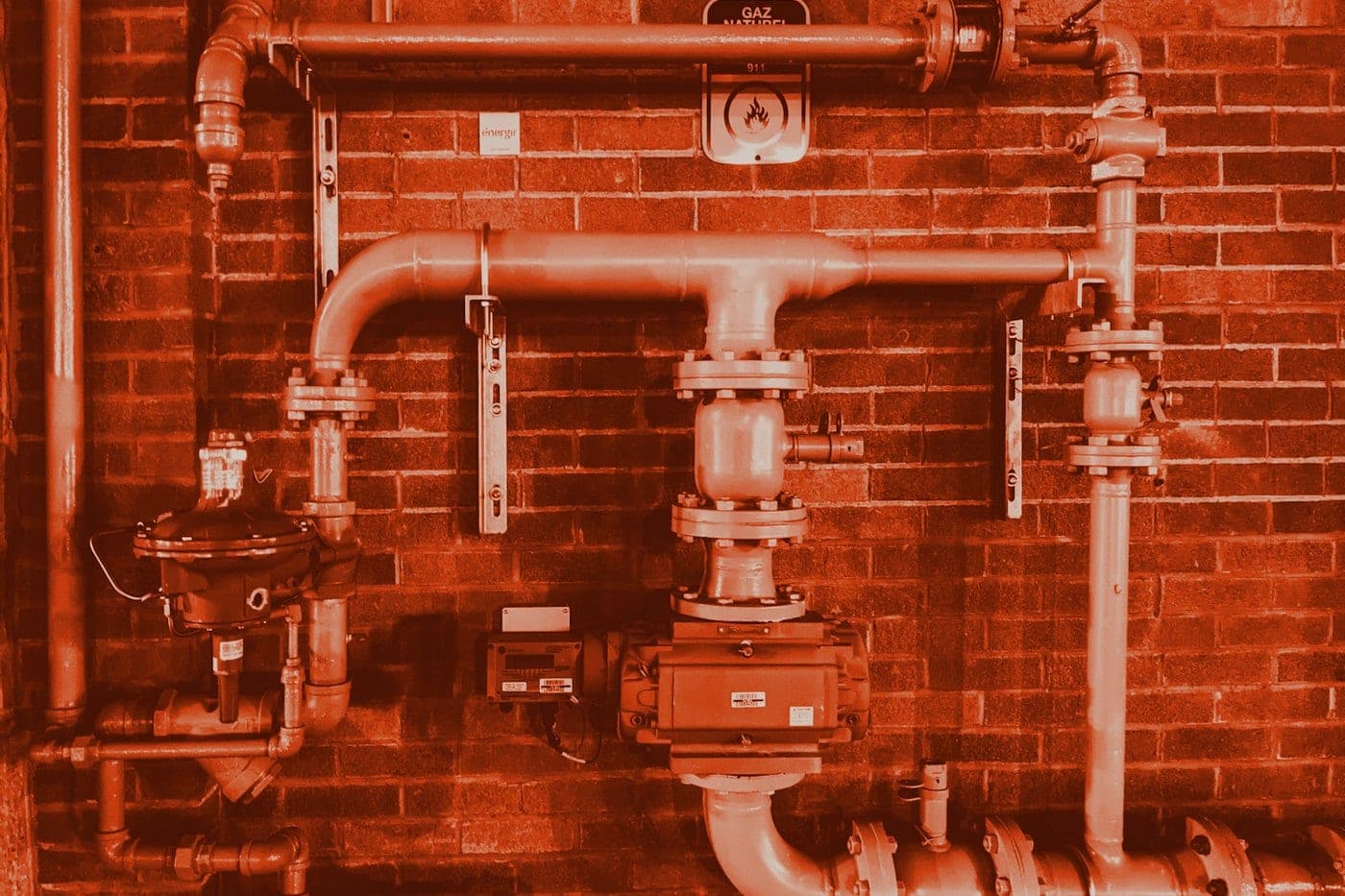 Site plumbing and pipework on a brick wall.