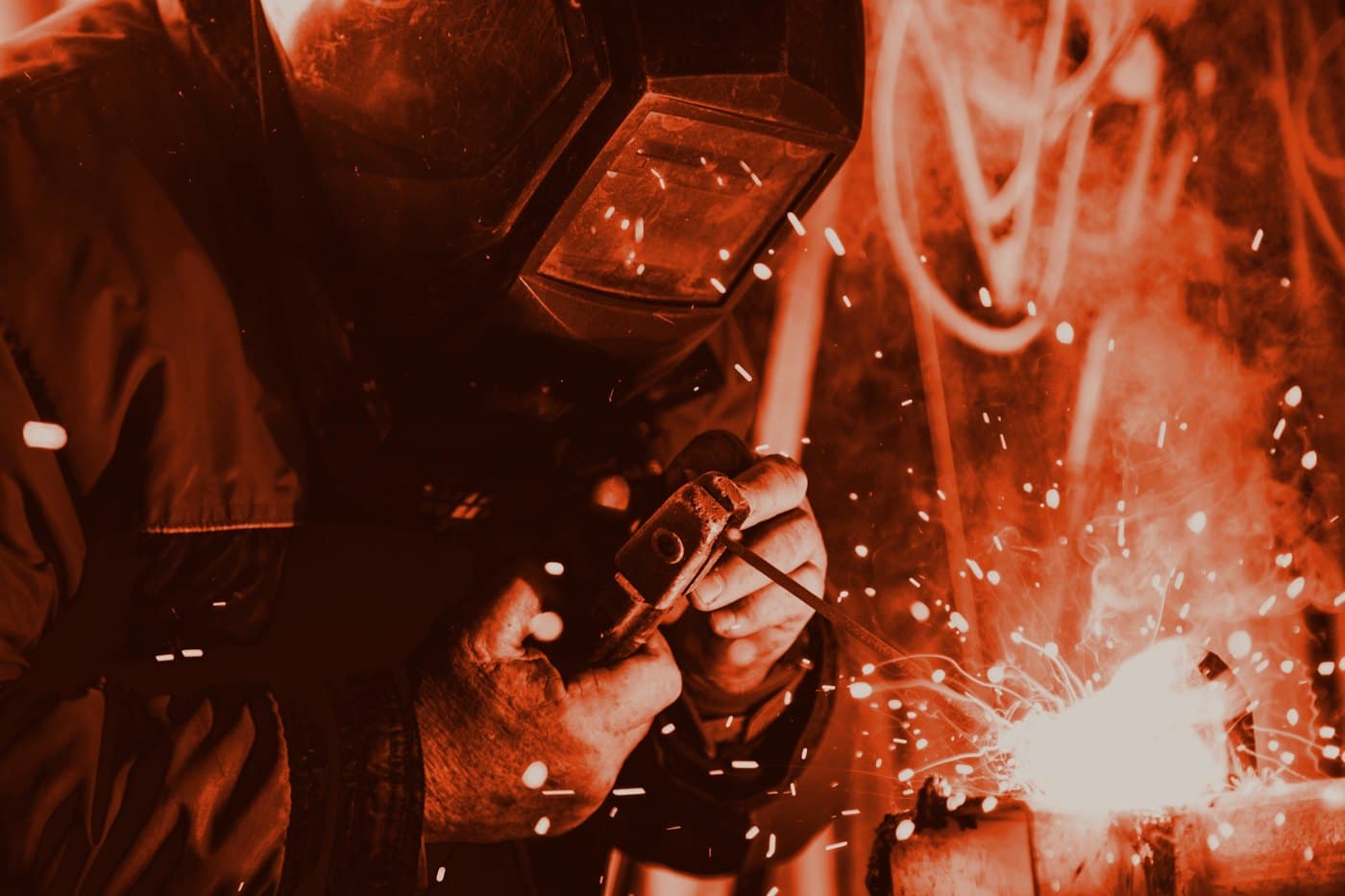 A welding helmet and spark on steel — face covered.